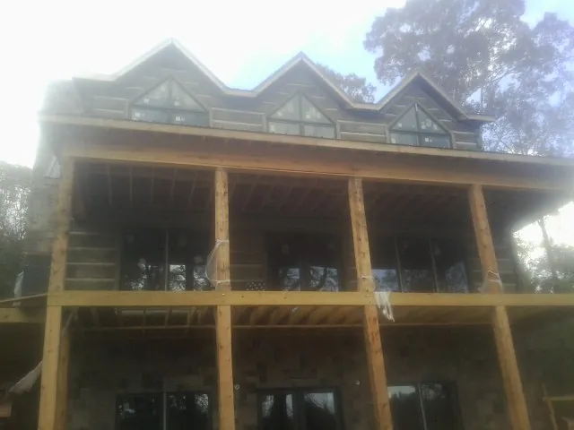Dormers and porch framing on a large log home under construction — Roof Coating work by our crew in Piedmont