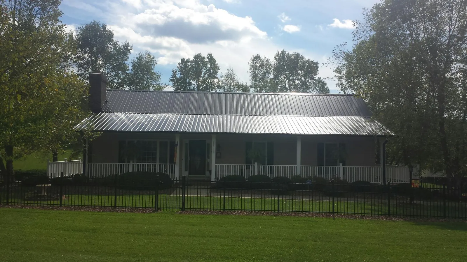 Gray metal roof on a brick ranch with a full width front porch — Gutter Guard Installation work by our crew in Piedmont
